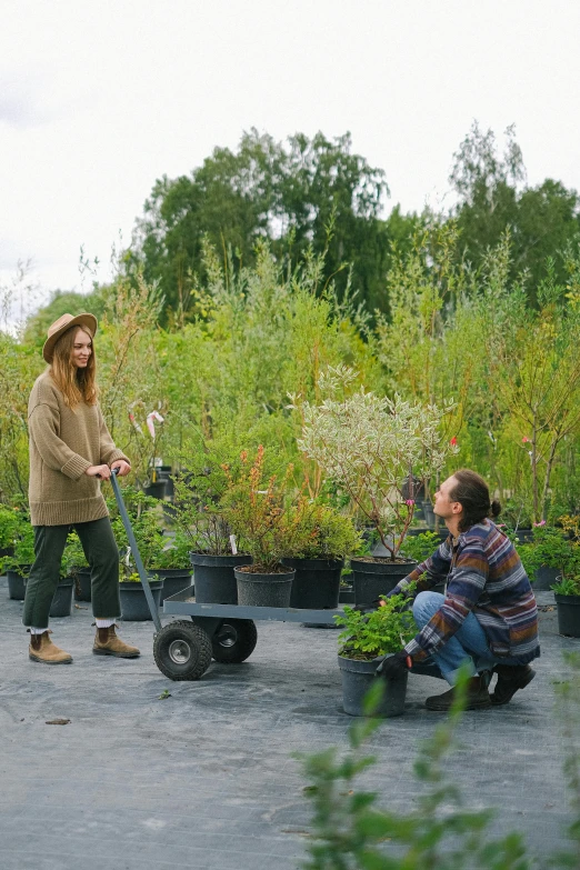a woman pushing a cart filled with potted plants, feels good man, willow plant, overlooking, dan mumfor