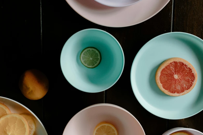 a table topped with bowls and plates filled with fruit, inspired by Évariste Vital Luminais, trending on unsplash, pink and teal, smooth matte, middle close up shot, enamel