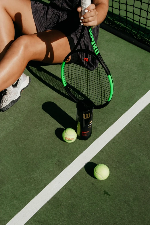 a woman sitting on top of a tennis court holding a racquet, monster energy drink, leg and thigh shot, zoomed in shots, clubs