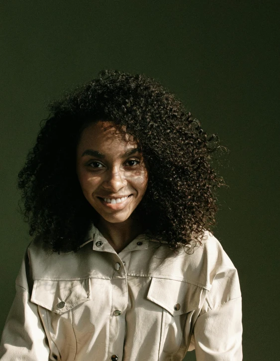 a woman with curly hair posing for a picture, inspired by Afewerk Tekle, trending on unsplash, hurufiyya, in a dark green polo shirt, wearing lab coat and a blouse, with textured hair and skin, smiling sweetly