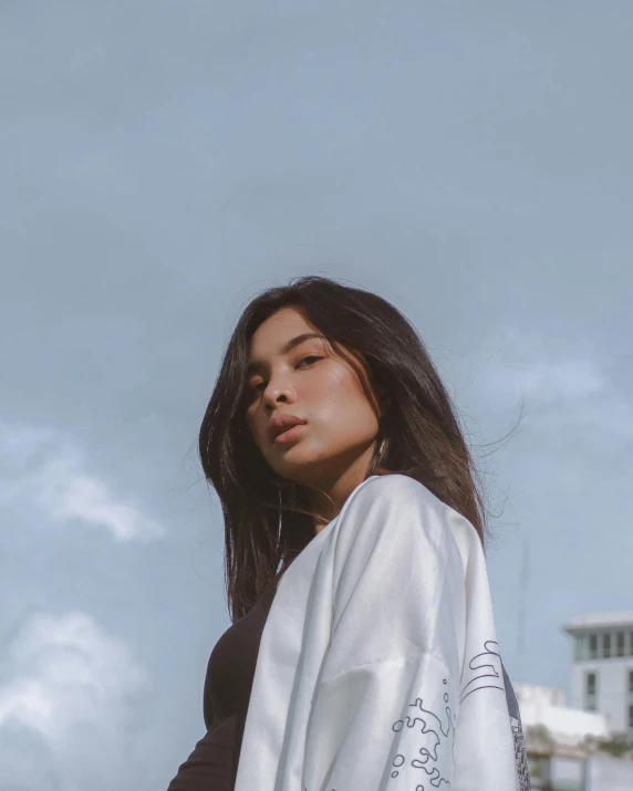 a woman standing on top of a beach next to the ocean, by Robbie Trevino, trending on pexels, dau-al-set, gemma chan girl portrait, wearing a robe, standing in a city street, androgynous face