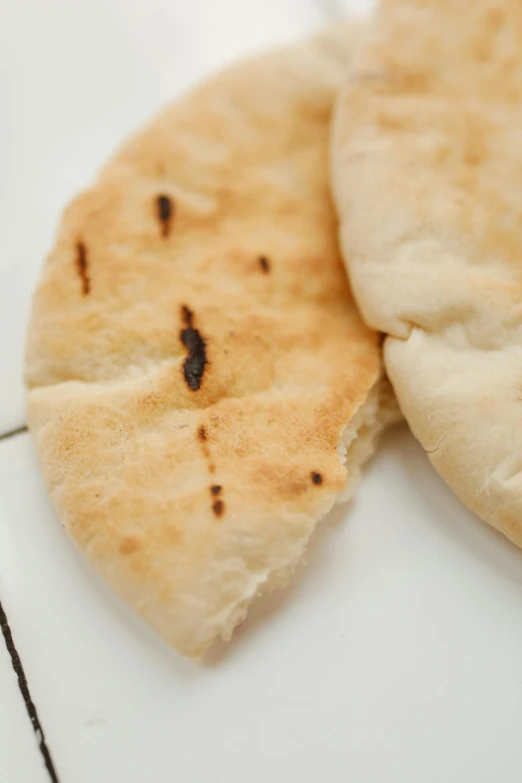 two pieces of bread sitting on top of a table, hurufiyya, oriental face, thumbnail, round-cropped, very crisp details