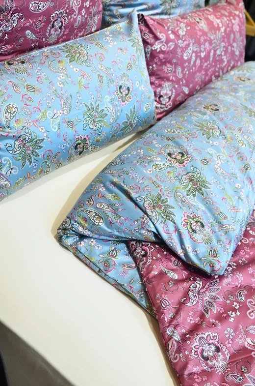 a couple of pillows sitting on top of a bed, by Ella Guru, baroque, mauve and cinnabar and cyan, body covers with neon flowers, medium close up, sleep