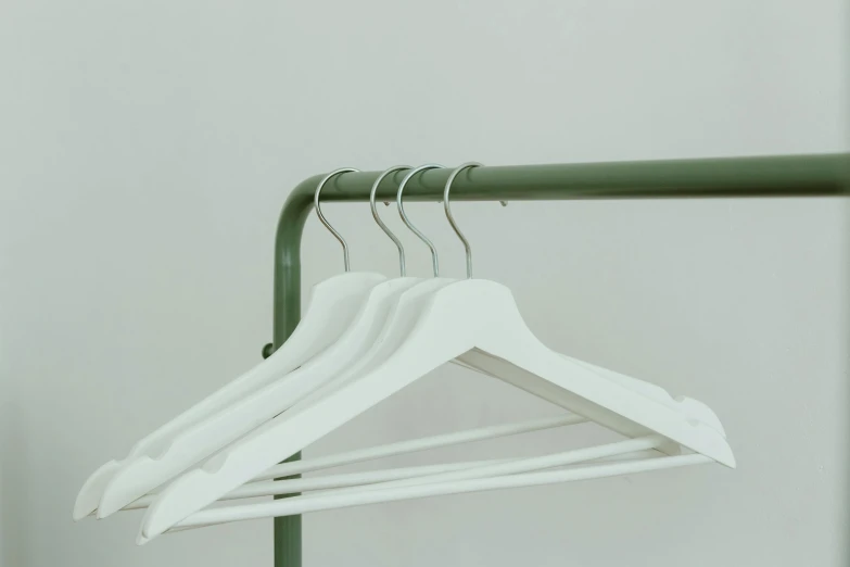 a white hanger sitting on top of a green rail, trending on pexels, white backdrop, multiple stories, garner holt, modeled