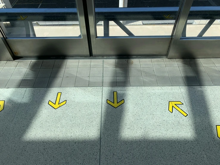 yellow arrows on the floor of an airport, by Carey Morris, temporary art, panels, 3 - piece, hovering indecision, no text