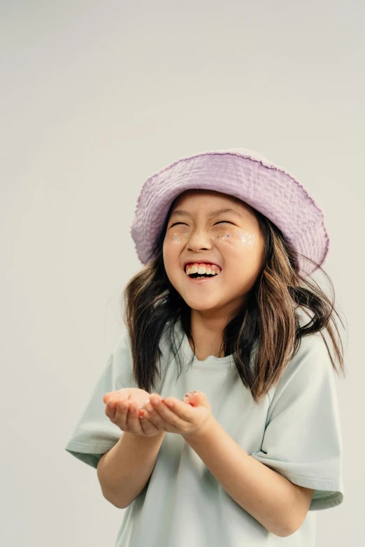 a little girl wearing a purple hat and smiling, by Juliette Leong, trending on unsplash, mingei, full view blank background, skincare, pastel hues, mutahar laughing