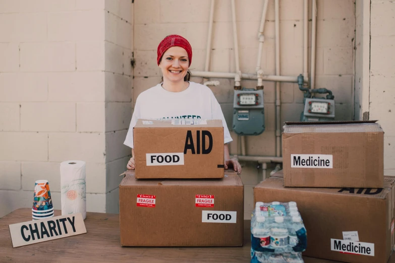 a woman standing in front of boxes of food, first aid kit, liam brazier, avatar image, candid portrait photo