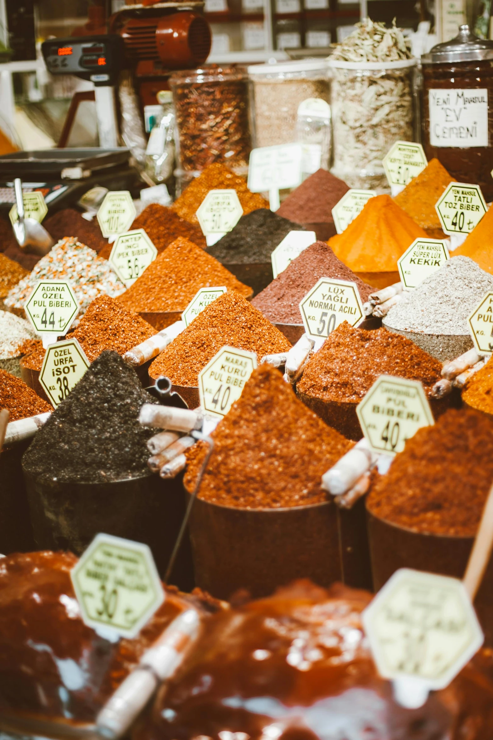 a display case filled with lots of different types of spices, a colorized photo, by Julia Pishtar, trending on pexels, istanbul, hexagonal shaped, colorful signs, cone shaped