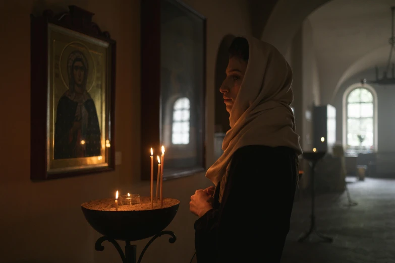 a woman holding a lit candle in a church, a picture, by Emma Andijewska, young middle eastern woman, production still, profile image, museum photo