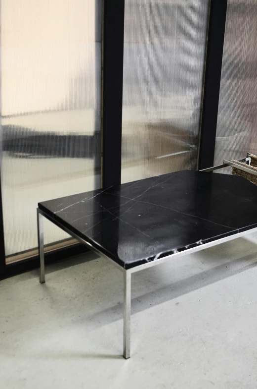 a black table sitting in front of a window, by Harvey Quaytman, unsplash, modernism, black marble, highly polished, on a coffee table, mezzanine