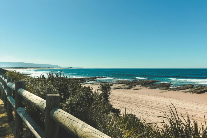 a wooden fence on a beach next to the ocean, unsplash, happening, bulli, clear skies in the distance, rock pools, 💋 💄 👠 👗