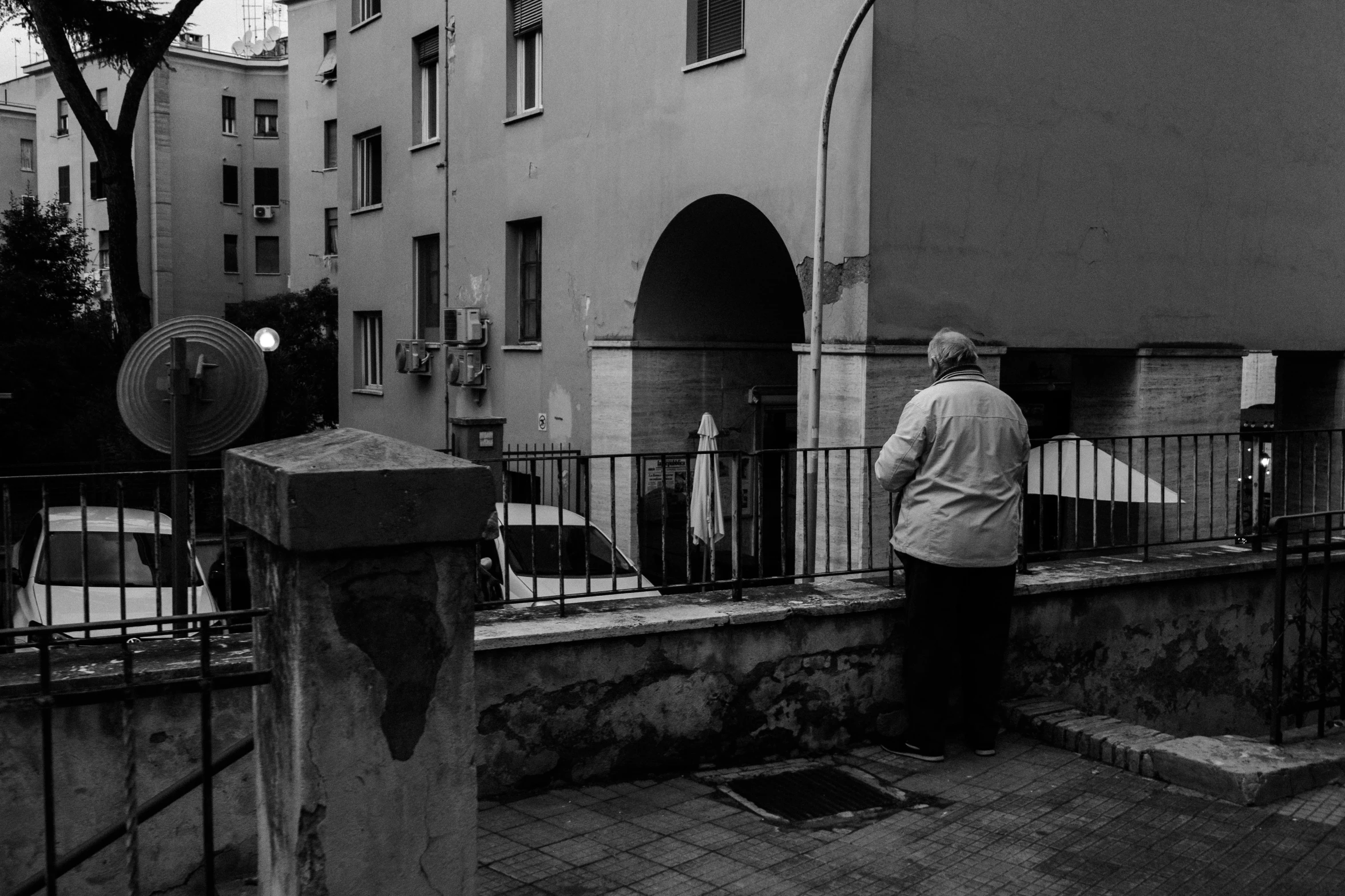 a black and white photo of a man standing in front of a building, a black and white photo, by Tamas Galambos, an old lady, people watching around, parce sepulto, white-haired