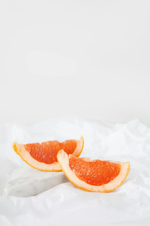 two slices of grapefruit sitting on a bed, a picture, by Julian Allen, trending on pexels, made of lab tissue, parchment paper, background image, 王琛