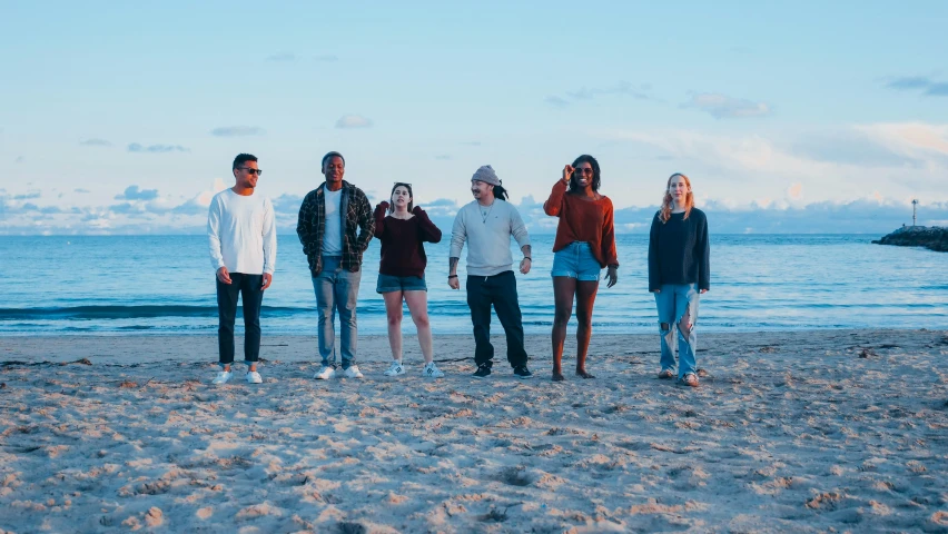 a group of people standing on top of a sandy beach, an album cover, pexels contest winner, mix of ethnicities and genders, calmly conversing 8k, college, unedited