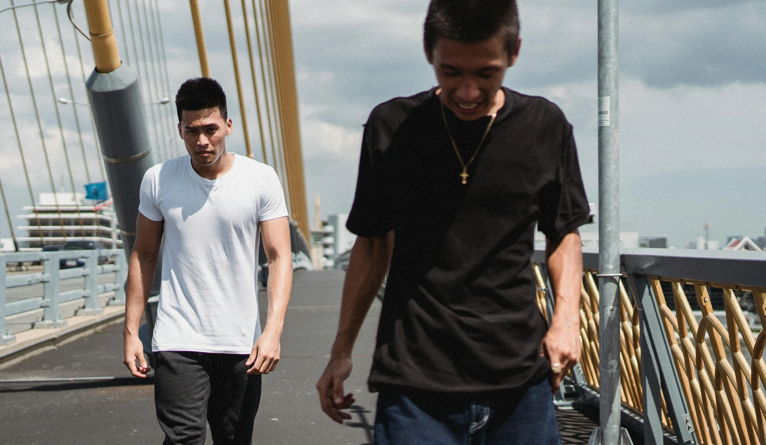 a couple of men riding skateboards across a bridge, a picture, pexels contest winner, asian descent, jeans and t shirt, bowater charlie and brom gerald, band promo photo