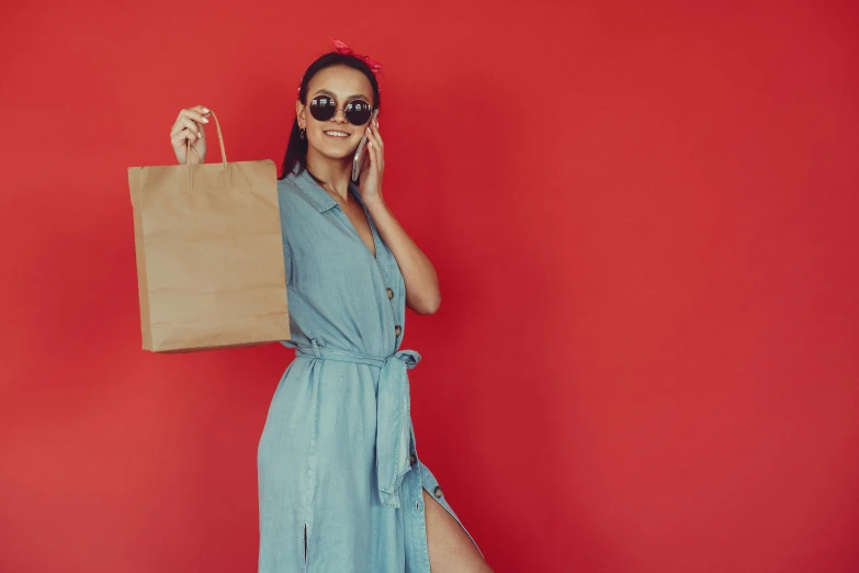 a woman in a blue dress holding a shopping bag, pexels contest winner, minimalism, in red background, tan skin, 15081959 21121991 01012000 4k, woman with rose tinted glasses