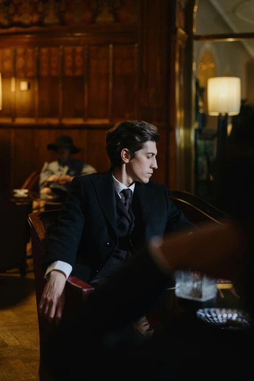 a man in a suit sitting in a chair, trending on pexels, renaissance, 1 9 2 0's style speakeasy, cai xukun, adam driver, hotel room