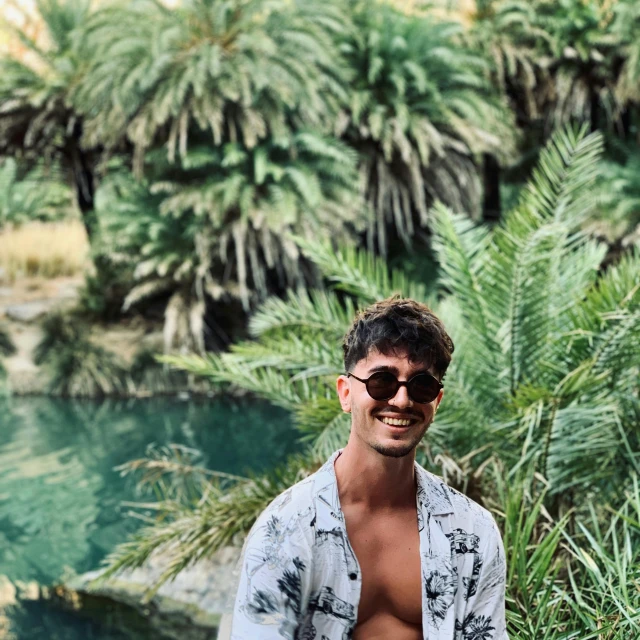 a man standing next to a body of water, an album cover, pexels contest winner, sumatraism, lush oasis, taking control while smiling, lachlan bailey, in spain