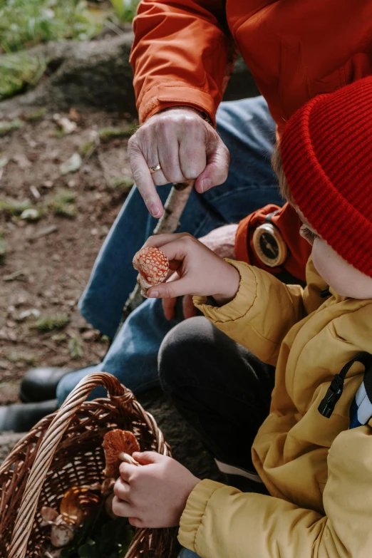 a man and a child are sitting on the ground, pexels contest winner, amanita muscaria, s'mores, beanie, detail shot