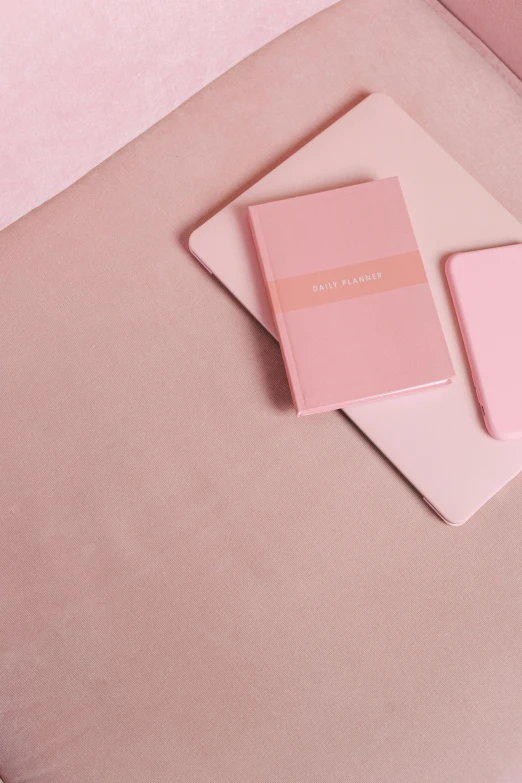 a couple of notebooks sitting on top of a pink couch, by Julia Pishtar, trending on unsplash, covered with pink marzipan, pastel pink skin tone, phone wallpaper, rounded corners