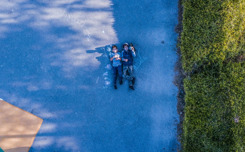 two people sitting on a bench in a park, a picture, by Jan Rustem, pexels contest winner, top down camera angle, blue, on a road, laying on the ground