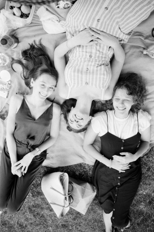 a group of people laying on top of a bed, inspired by Ruth Orkin, 3 young and beautiful women, picnic, profile image, movie promotional image