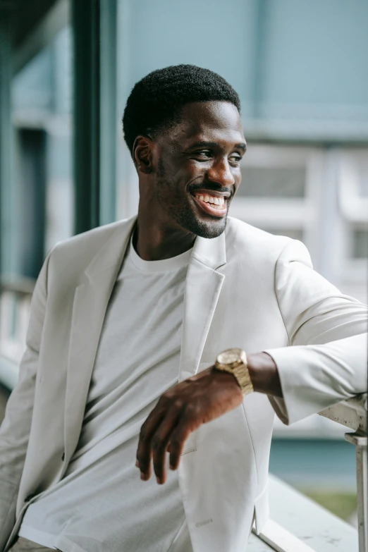 a man in a white suit leaning against a railing, inspired by David Bailly, pexels contest winner, smiling :: attractive, jaylen brown, portrait of tall, gold suit