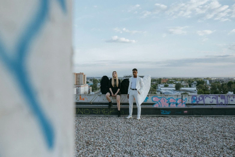 a couple of men sitting on top of a building, an album cover, unsplash, albuquerque, male and female, background image, anna nikonova