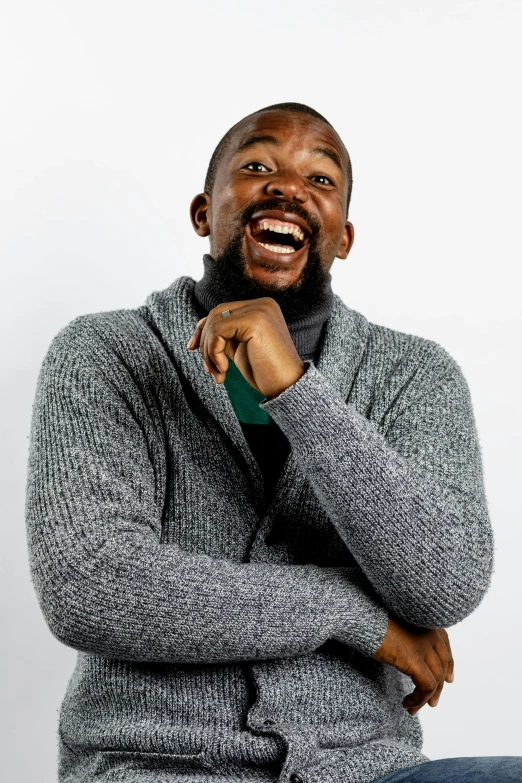 a man that is sitting down with his hand on his chin, inspired by Oluf Høst, happening, laughing out loud, wearing a green sweater, mkbhd as iron man, standup comedian