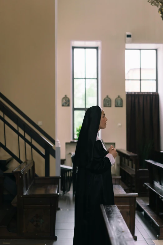 a woman in a black robe standing in a church, by Attila Meszlenyi, trending on unsplash, scene from live action movie, nun outfit, 15081959 21121991 01012000 4k