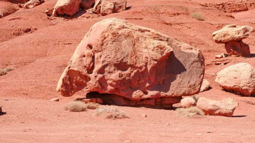 a large rock sitting in the middle of a desert, inspired by Albert Namatjira, pexels contest winner, figuration libre, dull red, head down, ((rocks)), brightly coloured