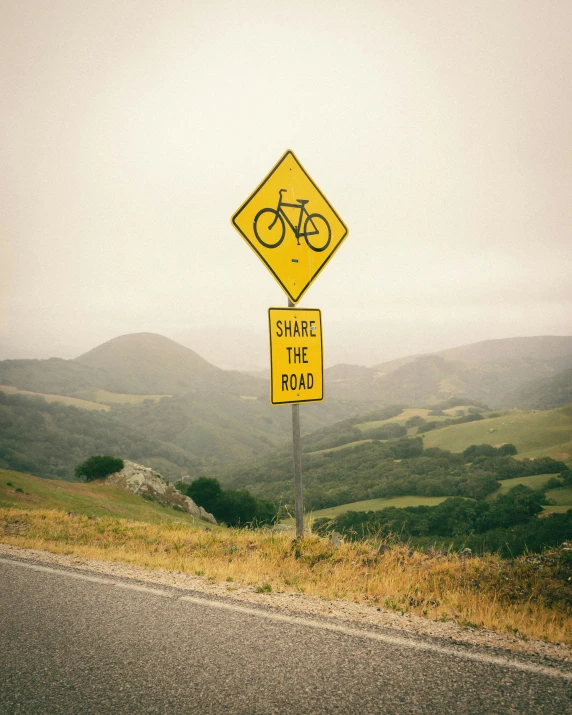 a yellow sign sitting on the side of a road, pexels contest winner, riding a bike, rolling hills, camaraderie, cupertino