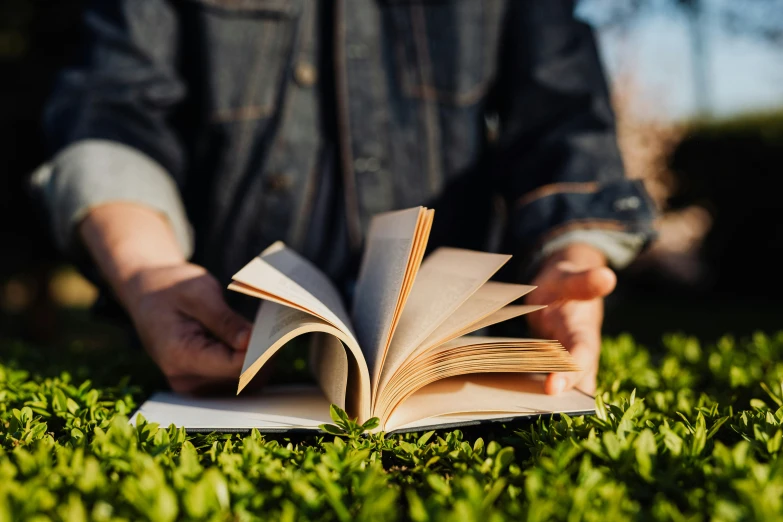 a person sitting in the grass reading a book, pexels contest winner, sustainable materials, avatar image, opening shot, 1 2 9 7