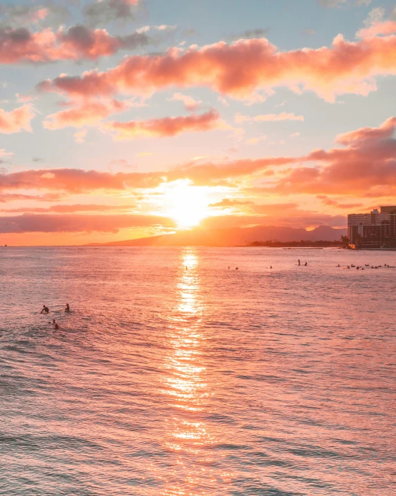 a group of people riding surfboards on top of a body of water, which shows a beach at sunset, waikiki beach, photo of the middle of the ocean, ((sunset))