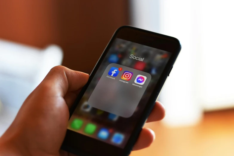 a close up of a person holding a cell phone, pexels, logo for a social network, square, at home, facebook post