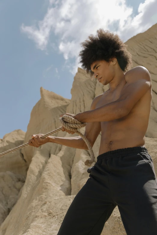 a man is pulling a rope in the desert, pexels contest winner, renaissance, black teenage boy, mid-shot of a hunky, video still, afro