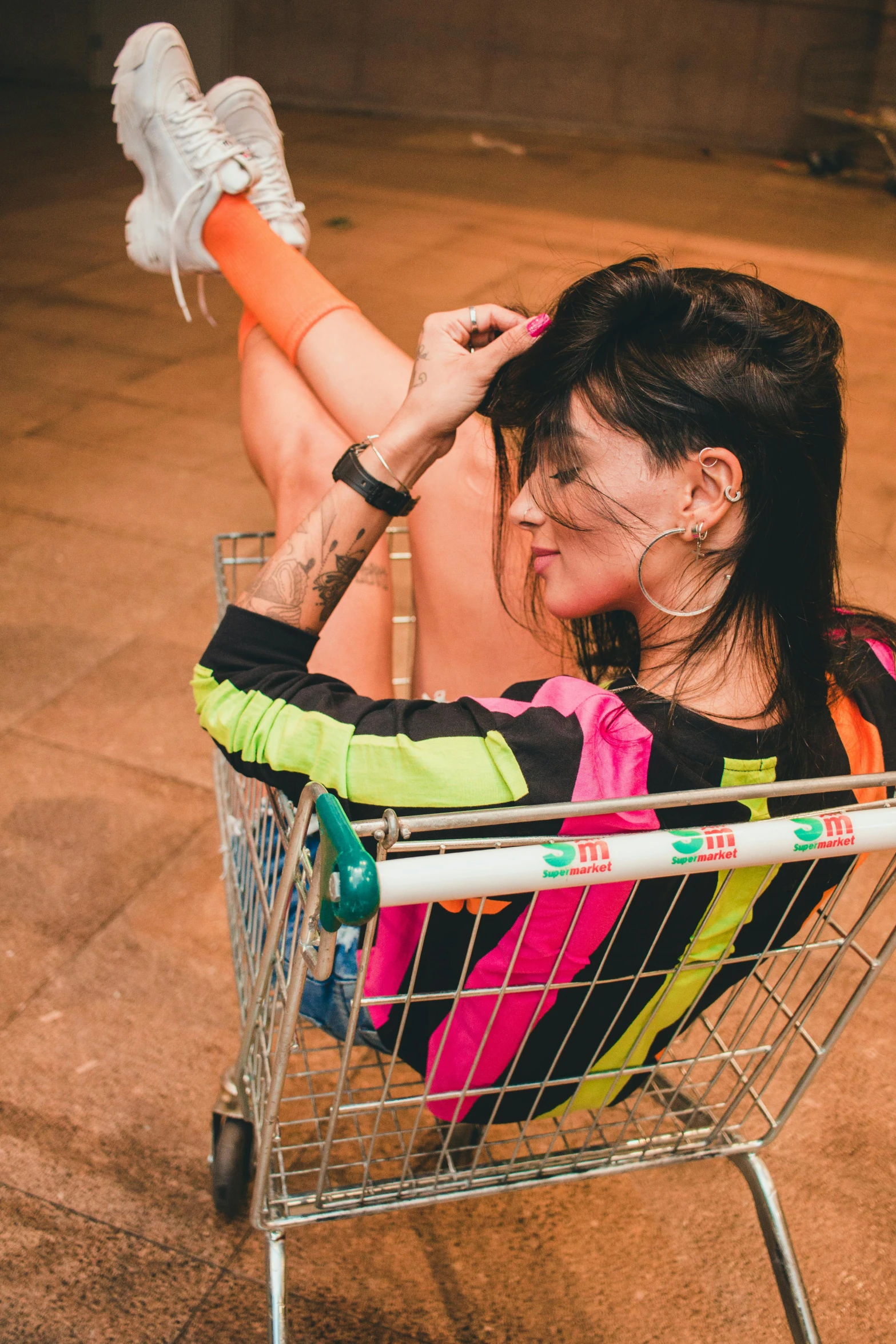 a woman is sitting in a shopping cart, inspired by Elsa Bleda, pexels contest winner, graffiti, colorful pigtail, woman with black hair, ripped clothing, low quality photo