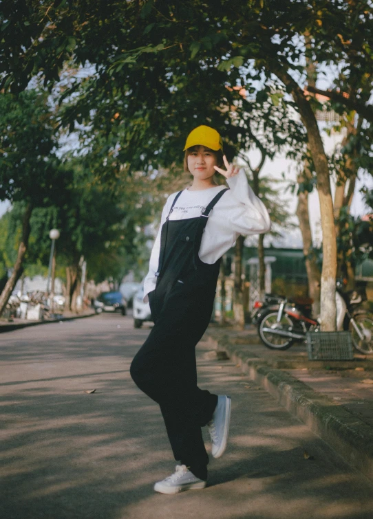 a man standing on the side of a road talking on a cell phone, a picture, inspired by Gang Hui-an, unsplash, yellow cap, 🤤 girl portrait, overalls, dang my linh