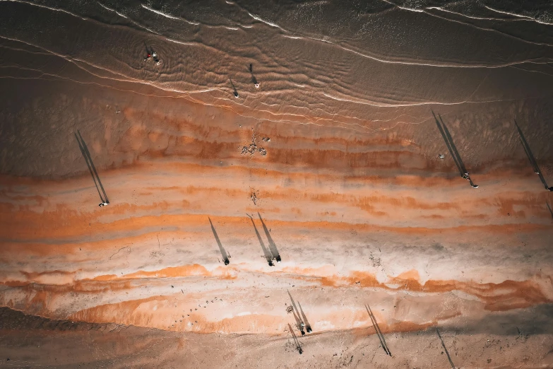 a group of people riding skis on top of a sandy beach, inspired by Andreas Gursky, unsplash contest winner, surrealism, mining outpost, dutch angle from space view, gray and orange colours, thumbnail