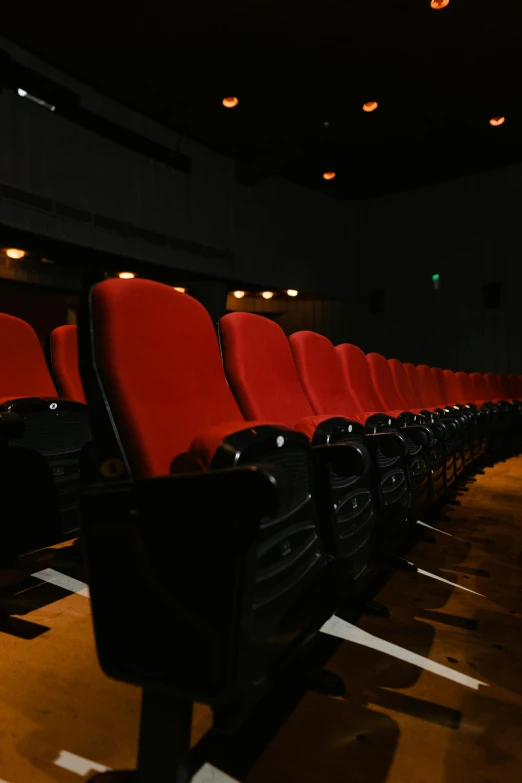 a row of red chairs sitting next to each other, in the spotlight, looking towards the camera