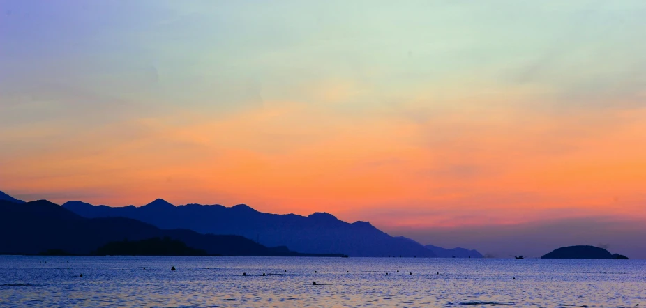 a large body of water with mountains in the background, by Carey Morris, pexels contest winner, romanticism, orange / pink sky, cannes, blue, indonesia