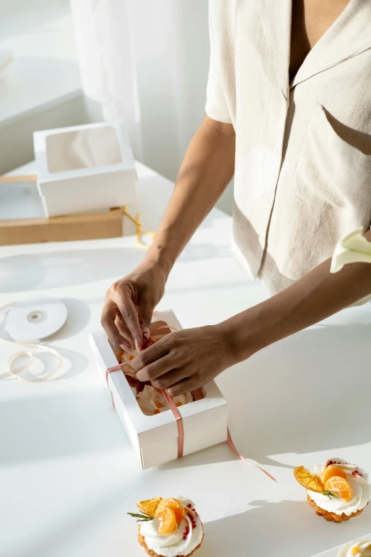 a close up of a person cutting food on a table, a marble sculpture, by Eden Box, ribbon, white box, stockphoto, bakery