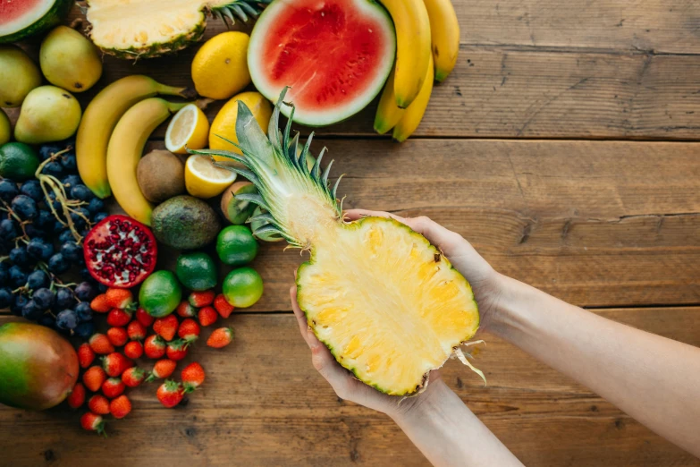 a person holding a pineapple in front of a pile of fruit, pexels contest winner, ingredients on the table, 🦩🪐🐞👩🏻🦳, no - text no - logo, background image