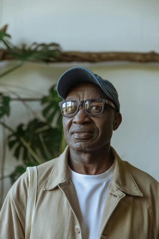 a man standing in front of a potted plant, by André Thomkins, pexels contest winner, photorealism, in square-rimmed glasses, wrinkly forehead, african man, 5 0 years old man