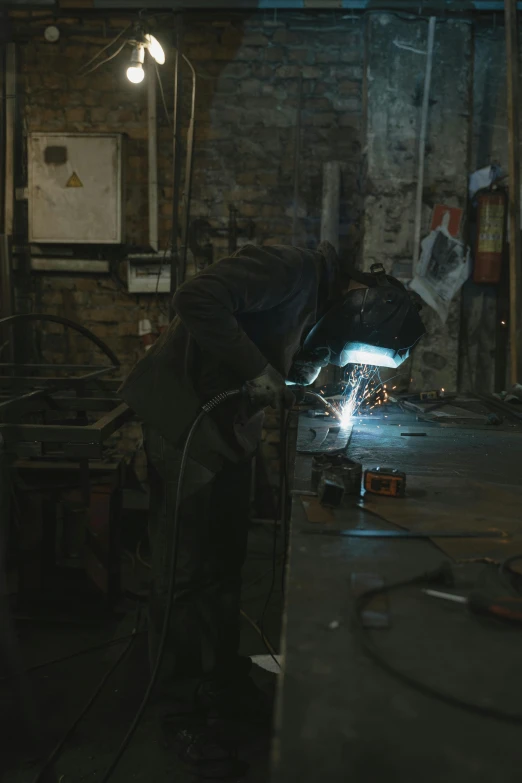 a man working on a piece of metal, by Thomas Furlong, worksafe. cinematic, ignant, [ metal ], amanda clarke