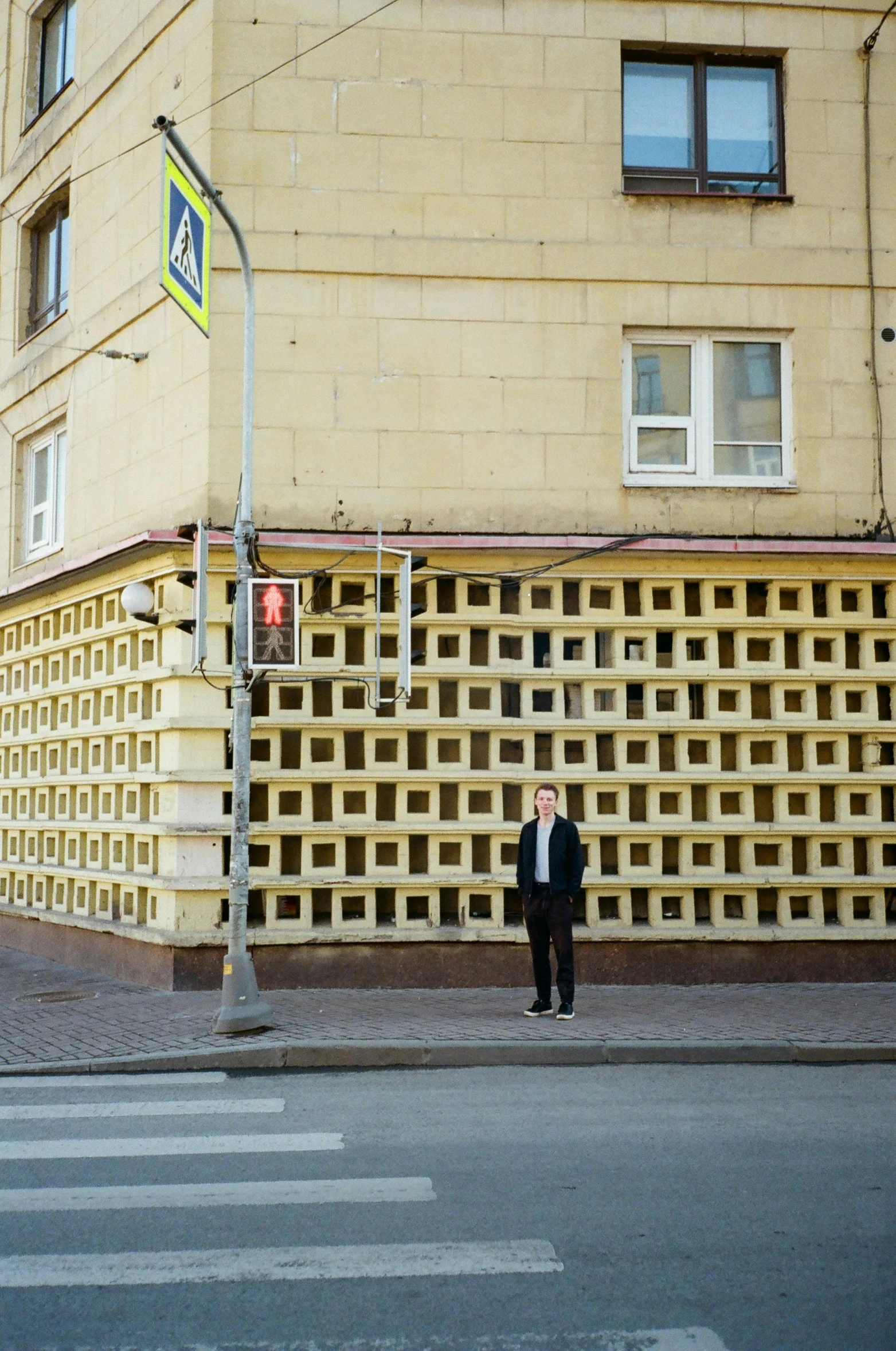 a man in a suit standing in front of a building, an album cover, inspired by Dmitry Levitzky, walls with tone of yellow, white block fence, khreschatyk, finland