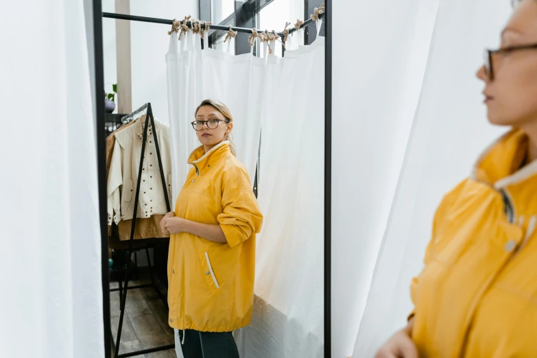 a woman standing in front of a mirror, trending on pexels, yellow raincoat, inspect in inventory image, casual clothing style, tall thin frame