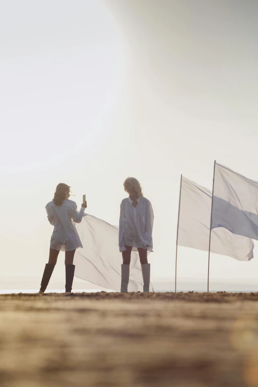 a group of people standing on top of a sandy beach, an album cover, by Romain brook, unsplash, conceptual art, holding a white flag, female sailor uniforms, flares, led zeppelin