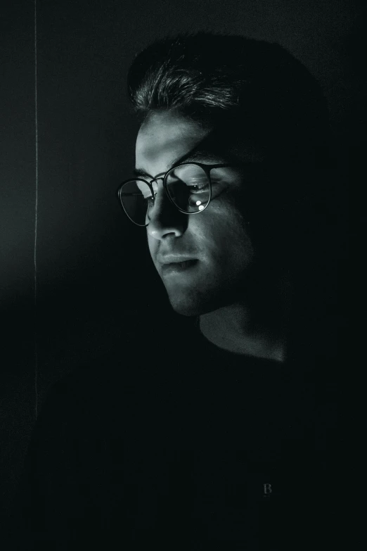 a black and white photo of a man wearing glasses, a black and white photo, unsplash, lowkey lighting, profile posing, photographed on colour film, **cinematic