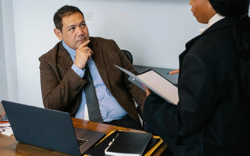 a man and a woman sitting at a table with laptops, by Robbie Trevino, lawyer clothing, looking around a corner, te pae, thumbnail